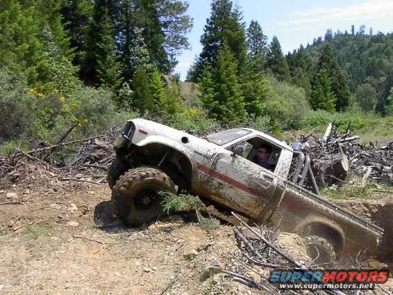 White pickup truck with large tires stuck in a ditch off-road