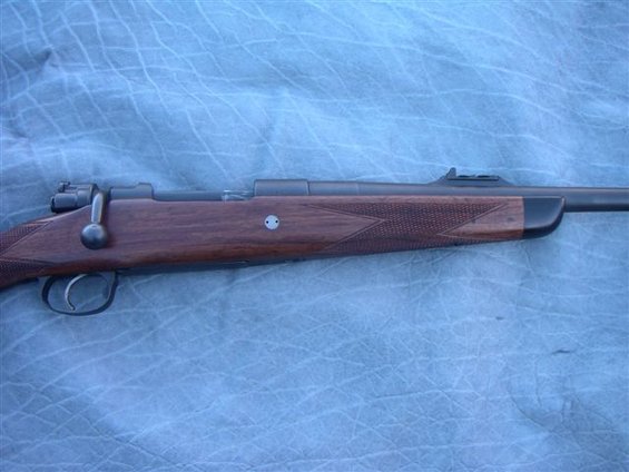 Side view of a wooden bolt-action rifle with a dark barrel and trigger assembly