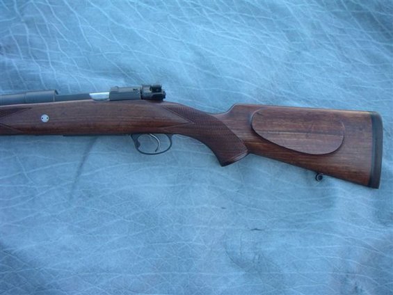 Wooden rifle stock with checkered grip and metal bolt mechanism visible