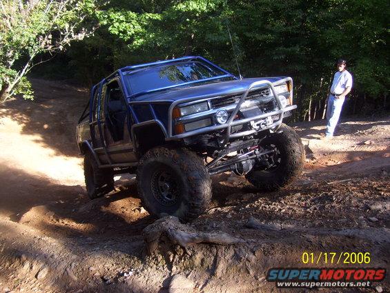Blue off-road SUV with custom roll cage and bull bar on a dirt trail