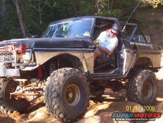 1978 Ford Bronco modified for off-roading, driver in seat, large tires, roll cage