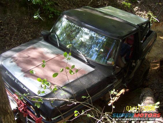 1978 Ford Bronco stuck in a dirt ditch, 'Alaskan Extreme' sticker on hood