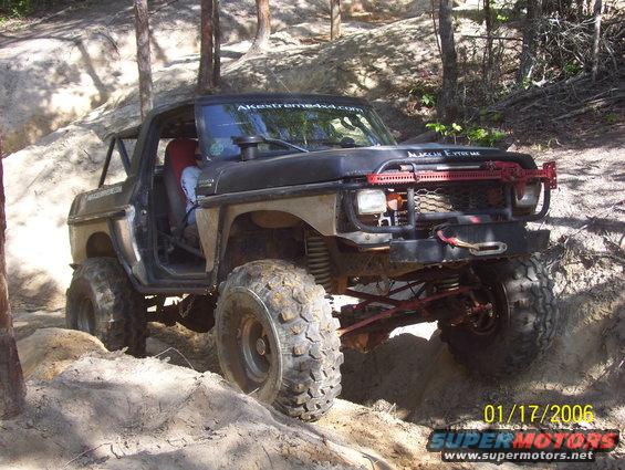 Black 1978 Ford Bronco off-roading, front view with red winch and grille guard