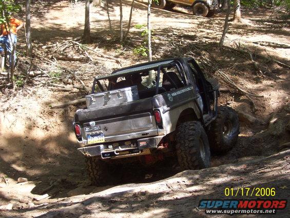 1978 Ford Bronco, black, off-road modified, rear view, on dirt trail with large tires and roll cage