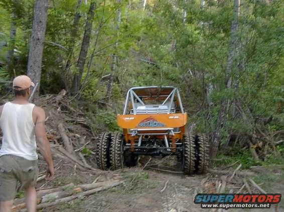 Orange off-road buggy with a roll cage and large tires, viewed from the rear