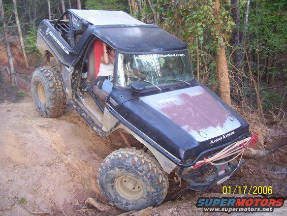 Modified SUV with big tires on a dirt trail. Text on windshield says the4x4.com. Text on front fender says ALASKAN EXTREME