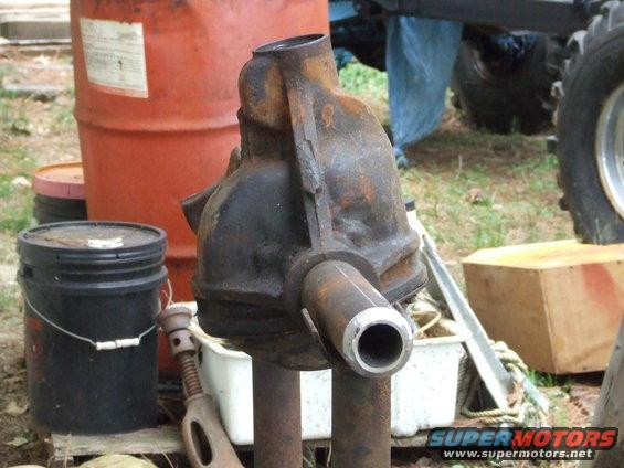 Rusty differential housing with cut pipes, next to orange barrel and black bucket