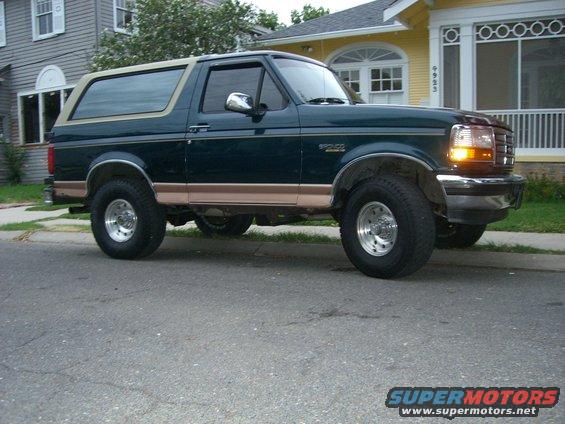 Dark green Ford Bronco with tan trim parked on a residential street, viewed from the front 3/4 angle