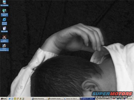 Person resting head on arm, computer desktop visible with icons and taskbar