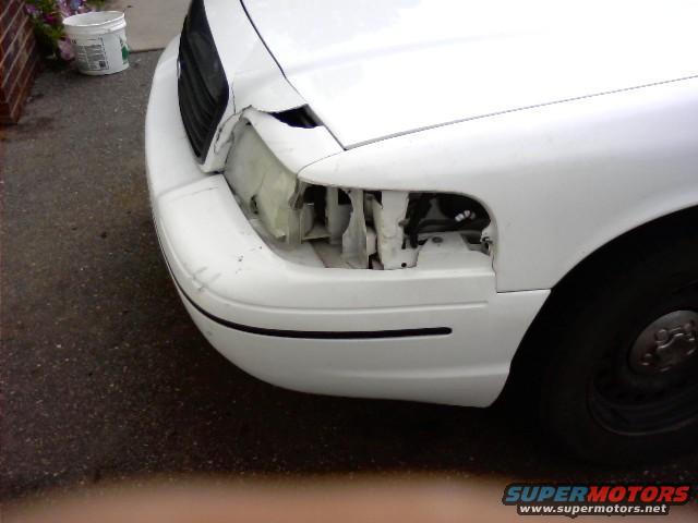 White 2000 Ford Crown Victoria front end with damaged headlight and grille