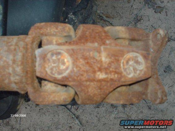 Close-up of a rusty driveshaft U-joint with visible grease fittings