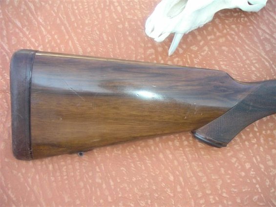 Wooden gun stock with dark butt plate and textured grip area