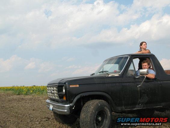 Black Ford Bronco with two people in a field of sunflowers