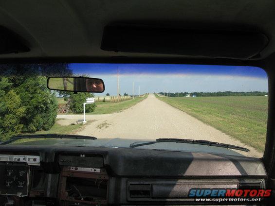 Interior view of a dirt road stretching to the horizon, with fields on either side