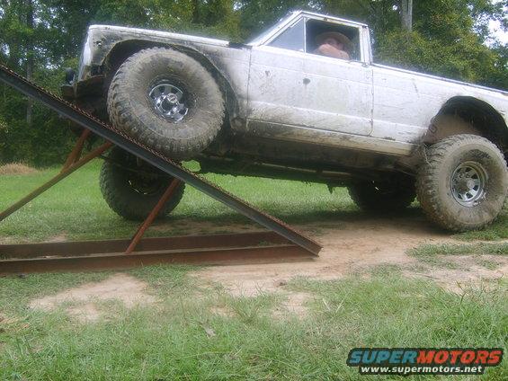 White pickup truck with large tires going up a metal ramp