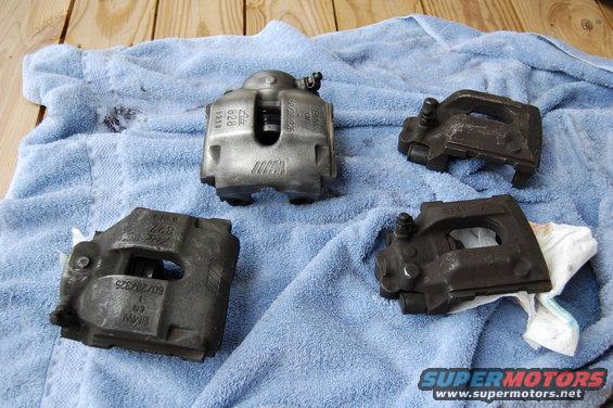 Four brake calipers, one with M logo, on blue towel