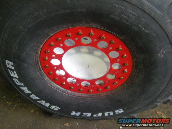 Close-up of a Super Swamper tire with a red beadlock and silver rim