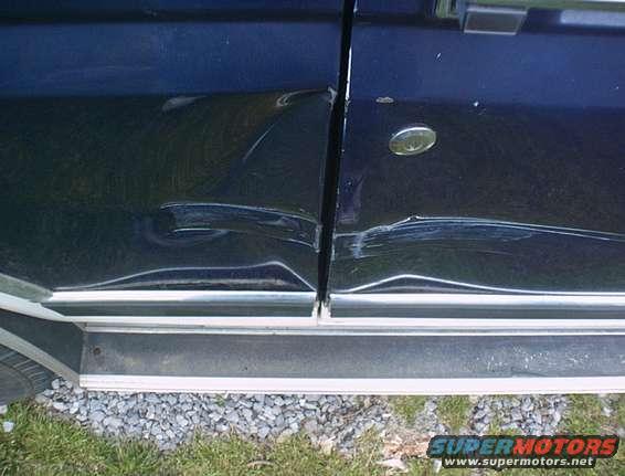 close-up of dented dark blue vehicle door and side panel