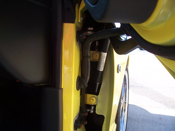 Yellow car door hinge and interior with visible text on a strut