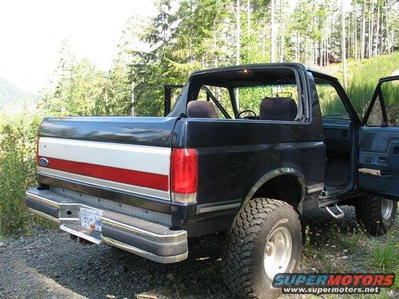 Rear view of black 1988 Ford Bronco with red and white tailgate stripe and off-road tires