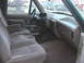 1988 Ford Bronco - The interior of a truck shows tan cloth seats, a center console with cup holders, and the dashboard.