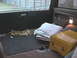 1988 Ford Bronco - The cargo area of a vehicle contains a folded blanket and a yellow case, with straps on the floor.