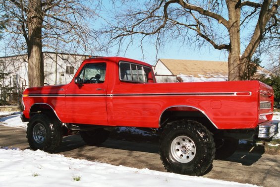 1979 Ford F-250 pickup truck, lifted with large tires, side view, red paint, snow on ground