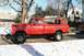 1979 Ford F-250 - A lifted red 1979 Ford F-250 pickup truck sits on a snowy street in front of houses and trees.
