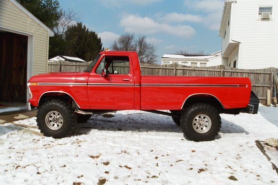 Side view of a red 1979 Ford F-250 pickup truck with lifted suspension and large tires
