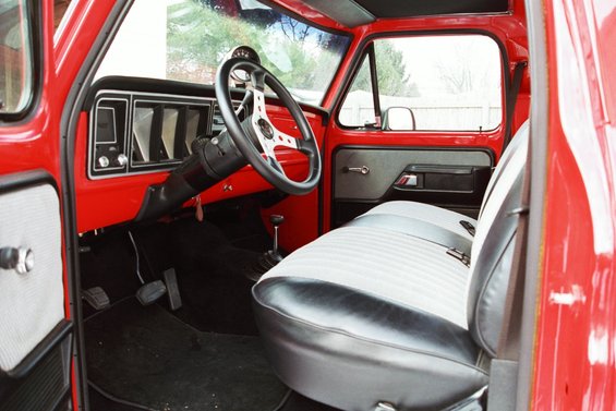 Interior of a red 1979 Ford F-250 pickup truck showing the dashboard, steering wheel, and bench seat