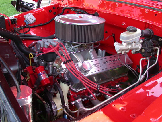 Close-up of a Ford Motorsports V8 engine with chrome valve covers and red spark plug wires