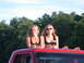 1979 Ford F-250 - Two women pose on the roof of a red truck, with trees and a blue sky in the background.