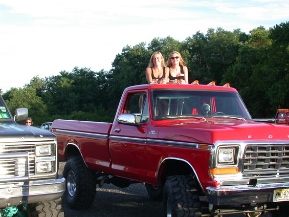 Red 1979 Ford F-250 pickup truck, lifted with large tires, viewed from the front-right
