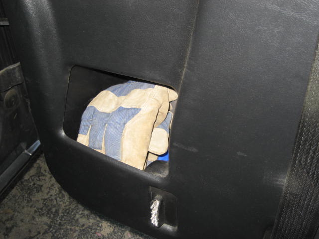 Interior view of a black plastic storage compartment holding a pair of blue and tan work gloves