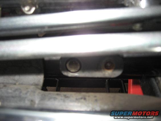 Close-up of metal frame parts with two bolt holes visible