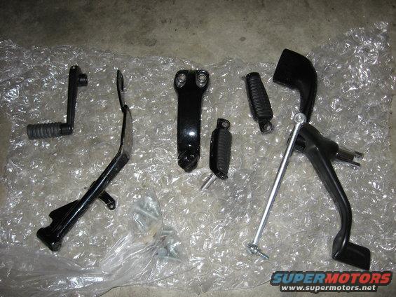 Motorcycle foot controls including shifter, brake pedal, and footpegs laid out on bubble wrap