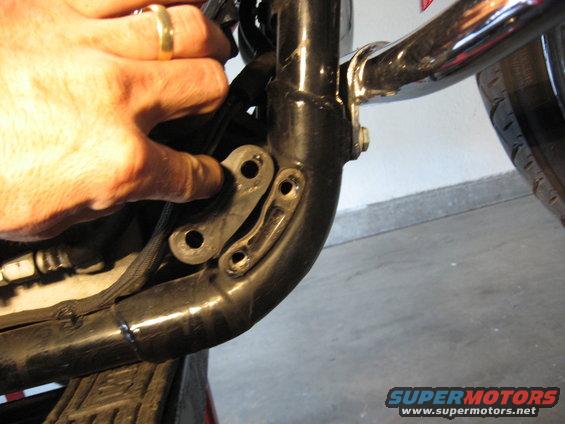hand pointing to bracket on black motorcycle frame