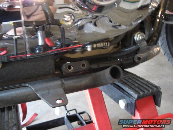 Motorcycle engine and frame parts on a red stand. Chrome engine casing reflects