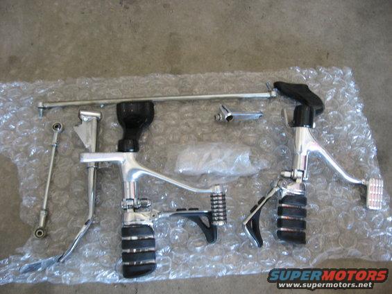 Chrome and black motorcycle foot controls laid out on bubble wrap