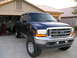 2001 Ford F-350 - This blue 2001 Ford F-350 pickup truck is shown from a 3q-front angle, parked in a driveway with a garage in the background.