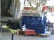 1964 Ford Galaxie - A blue V8 engine and transmission assembly is shown in a workshop setting, suspended by chains.