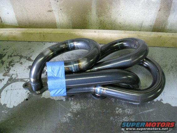 Exhaust manifold with blue tape on pipes, welded seams visible