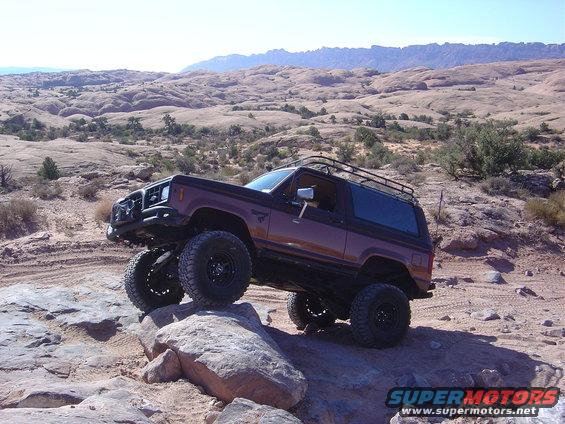 Brown Ford Bronco II with roof rack climbing rocks
