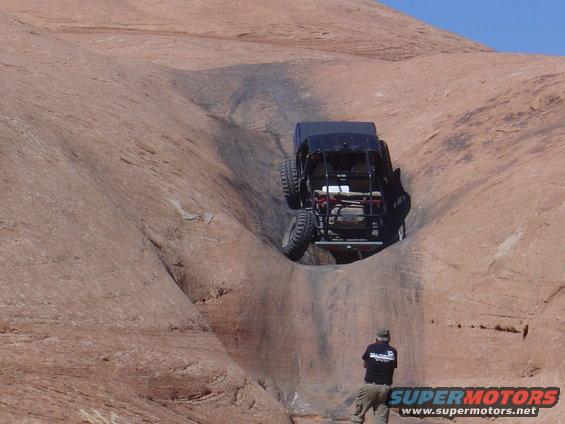 Black off-road vehicle climbing a steep rock face in Moab