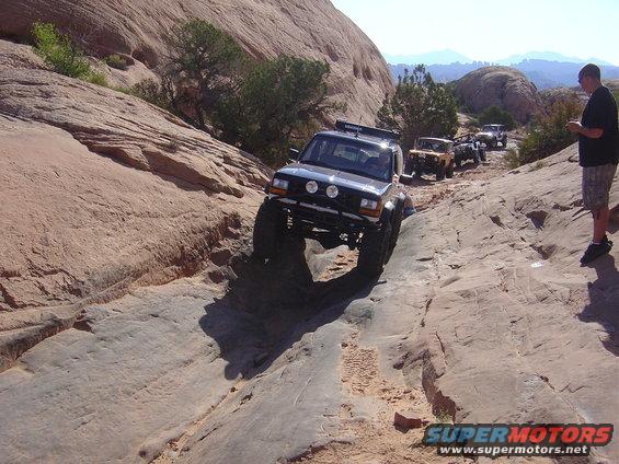 Four-wheel drive vehicles navigating a rocky trail, one in the foreground with large tires