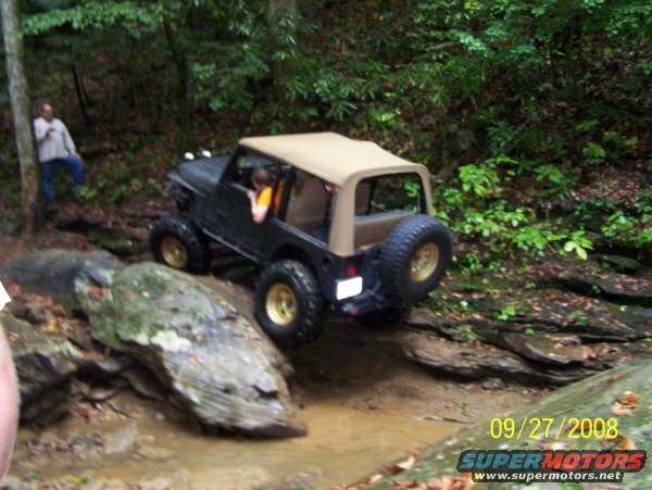 Black Jeep Wrangler off-road, tan soft top, gold wheels