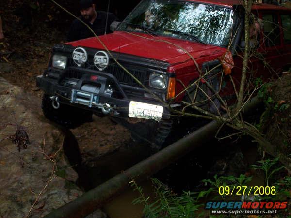 red 1992 Jeep Cherokee stuck in mud and water with a winch on the front bumper