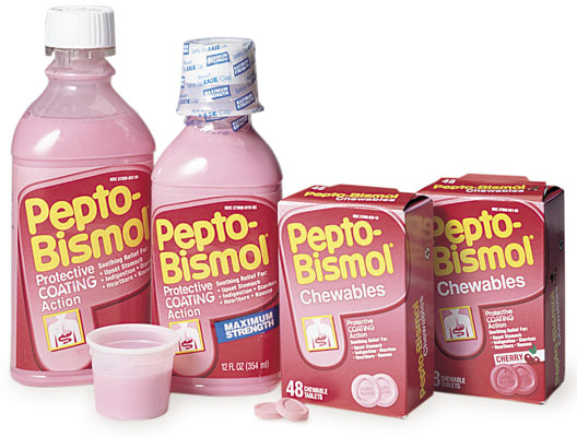 Two bottles and two boxes of Pepto-Bismol, with a small plastic cup and loose chewables