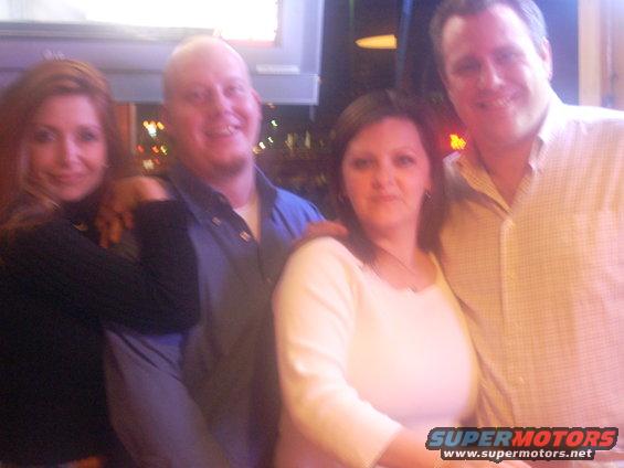 Four people, two men and two women, pose for a photo indoors