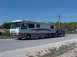 2002 Ford Supercrew - An RV is seen towing a pickup truck on a road under a clear blue sky.